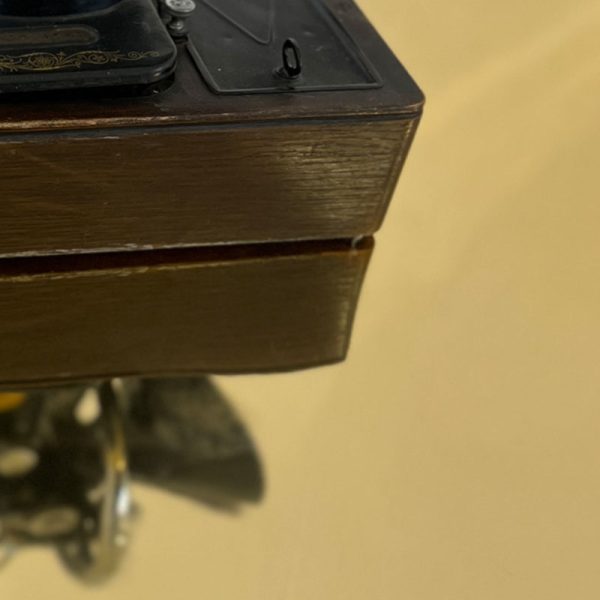A close up of gold mirror flooring from J&C Joel. The reflection shows part of a sewing machine on top of the mirror flooring, with its reflection being seen in the flooring itself.