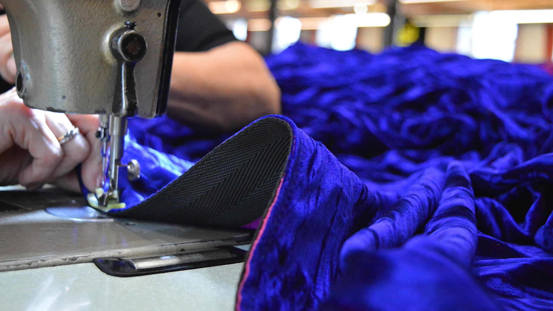 An image showing curtains, most likely theatre curtains, going through a sewing machine at J&C Joel.